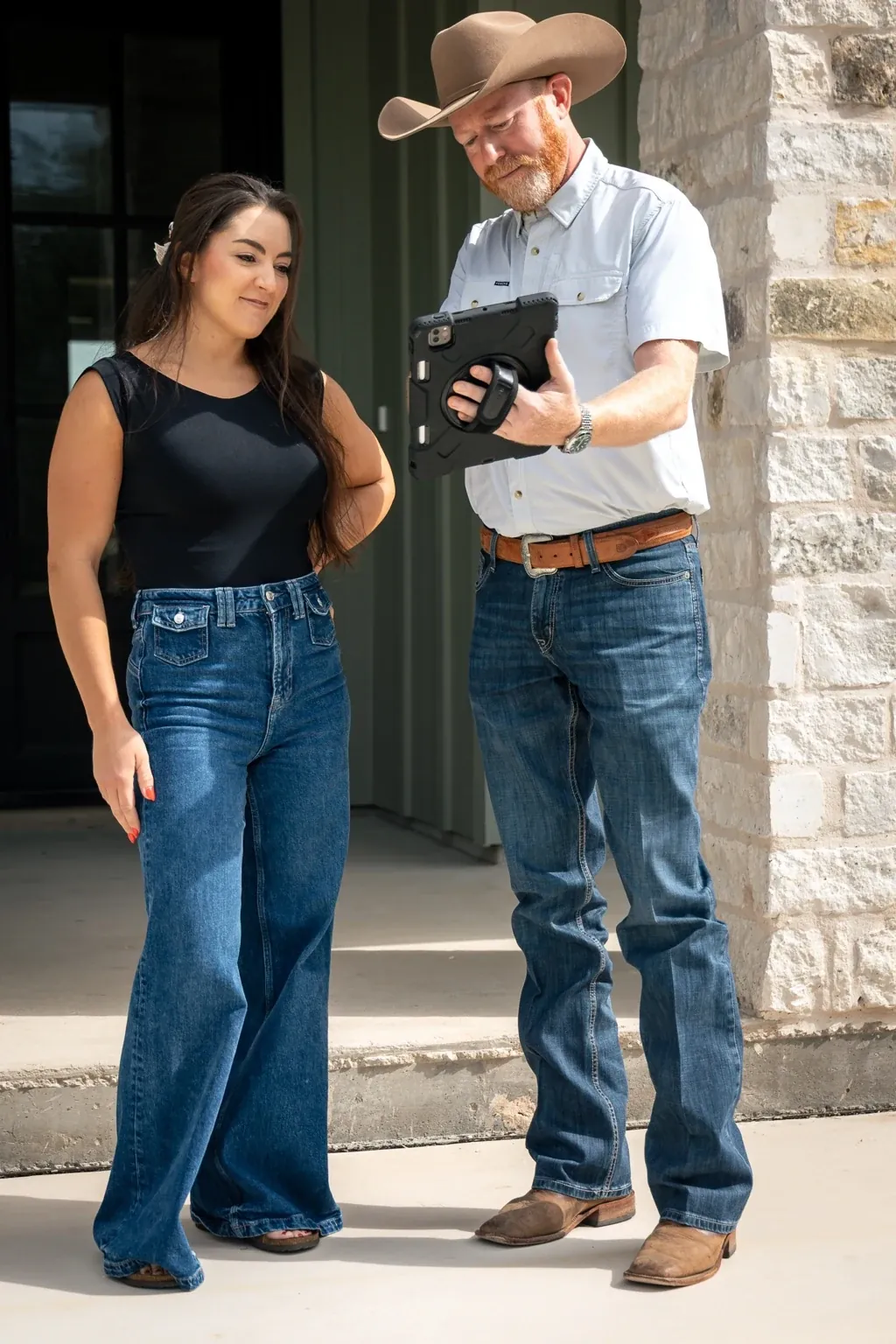 A Heritage team member and a homeowner review a tablet together outside a home.
